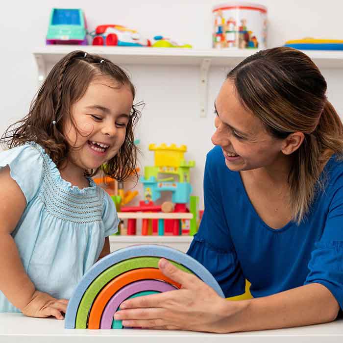 Two-year-old girl and her young kindergarten teacher, playing an